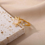 Gold ring with sun design on a beige stone surface